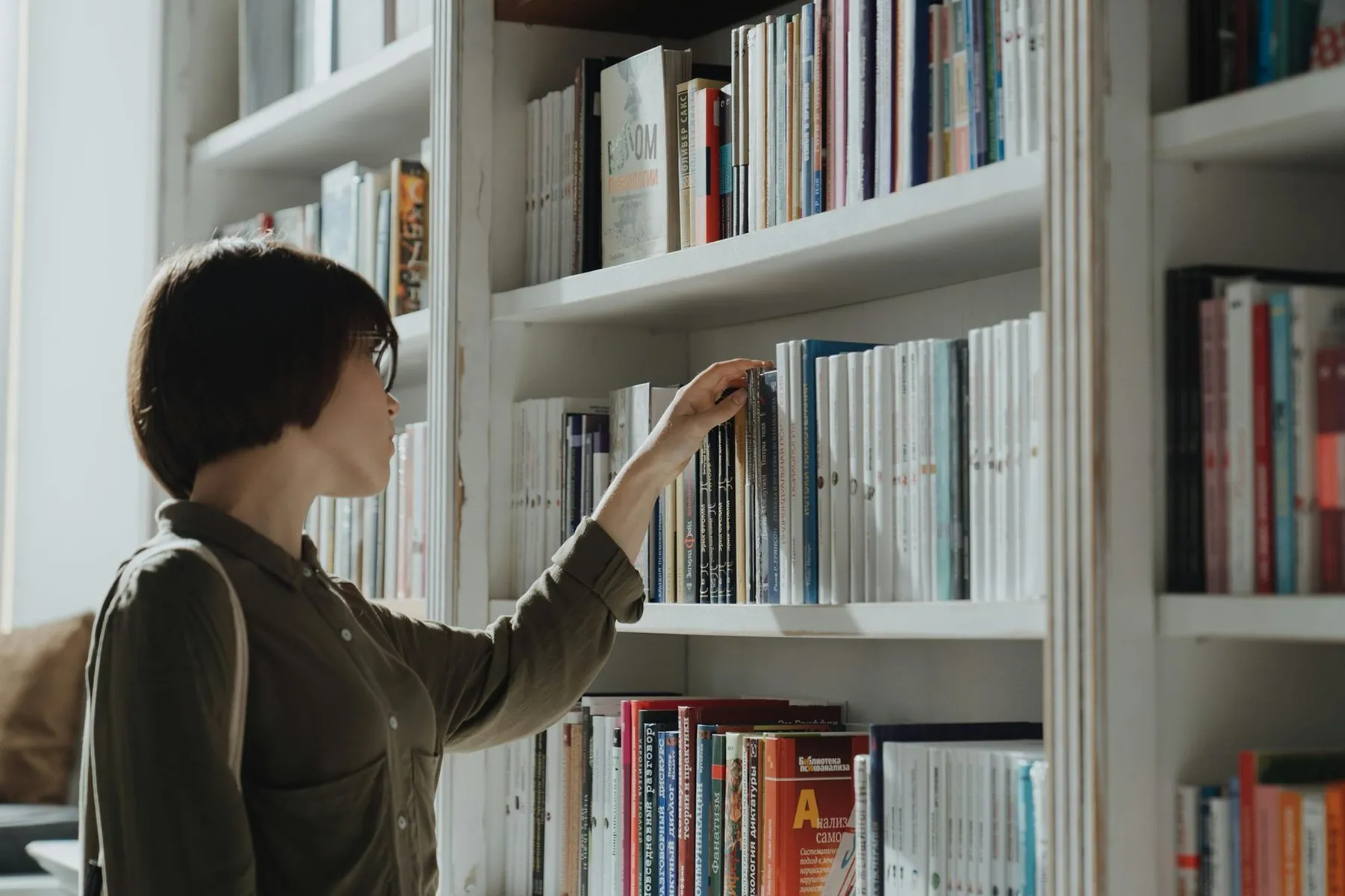 A woman browsing a bookshelf in a modern library setting exploring various literature options